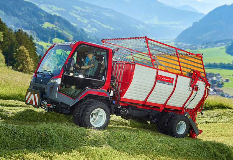 Roter Unitrac 122 LDrive mit Ladewagen-Aufbau bei der Grasernte