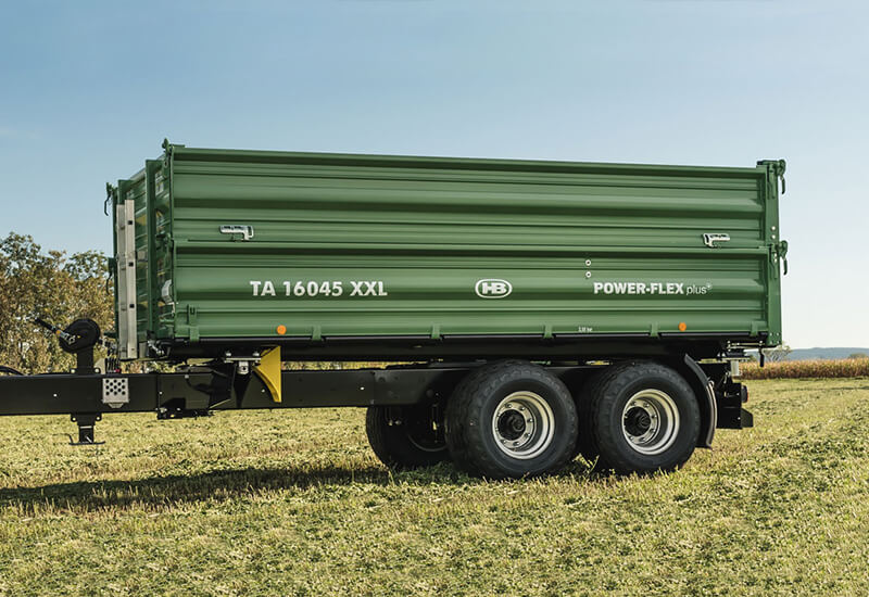 Brantner Tandem-Dreiseitenkipper mit Power-Flex+ Bordwandsystem auf einer Wiese bei sonnigem Wetter