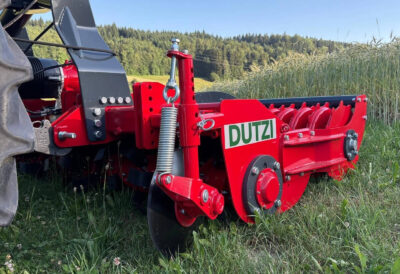 Dutzi Rotorkiller angehängt an einem Traktor im Einsatz neben einem Kornfeld